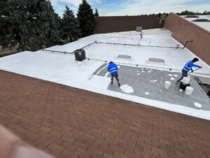 Guardian Roof Coating technician installing a roof restoration coating system on a flat roof
